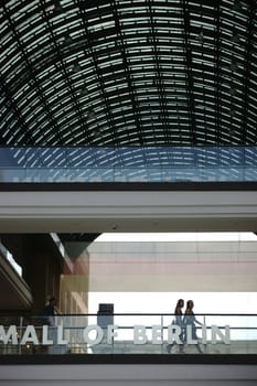 Berlin,Germany - June 21,2016: Guests and visitors walk across a bridge with glass railings under the roof of the Mall of Berlin shopping center on June 21,2016 in Berlin.