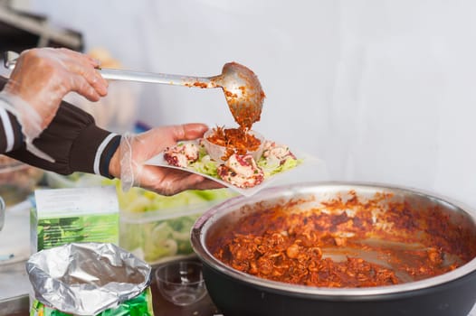 Street food. The hands of the chef prepare a dish of stewed cuttlefish.