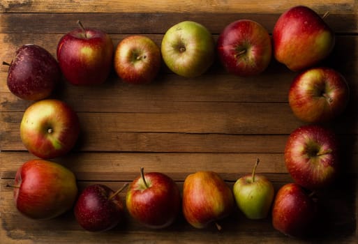Horizontal top view of organic small raw apples on vintage wood board with copyspace in the middle