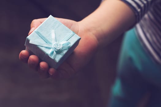 top view close up of child holding a blue gift box with ribbon in his hand