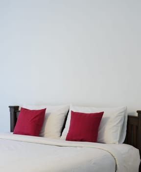 White bedroom with tidy bed and red pillows
