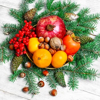 tangerines,pomegranates,persimmons and nuts,decorated with fir branches