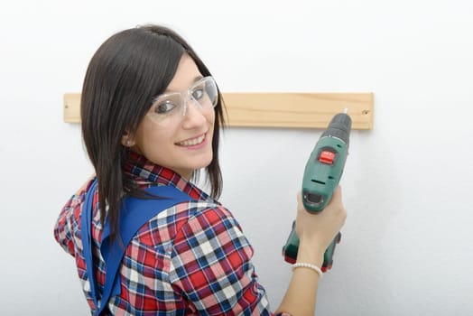 pretty young brunette woman holding cordless drill