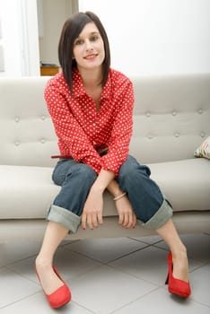 young brunette woman with jeans pants sitting in the sofa