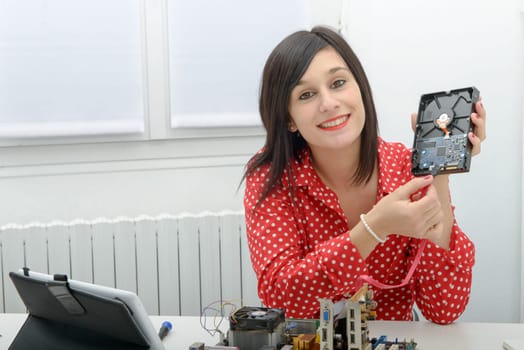 Young smiling brunette woman  technician repairs a computer