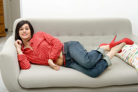 young brunette woman with jeans lying in the sofa