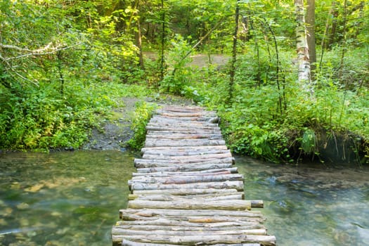 Homemade wooden bridge over a small river forest
