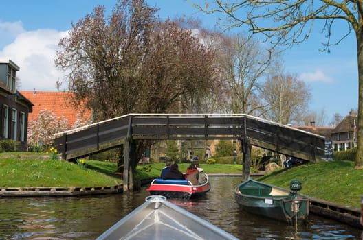 GIETHOORN, NETHERLANDS - APRIL 3, 2016: Unknown people in boats enjoying their sightseeing boat trip in a canal in Giethoorn, also often called the Venice of the North