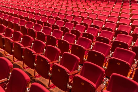 Rows of red color theatre chairs in conference room.