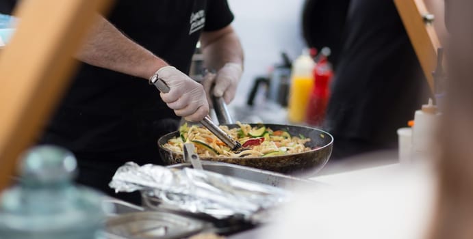 Cheff cooking traditional Japanese noodles on street stall on international street food festival of Odprta kuhna, Open kitchen event, in Ljubljana, Slovenia.