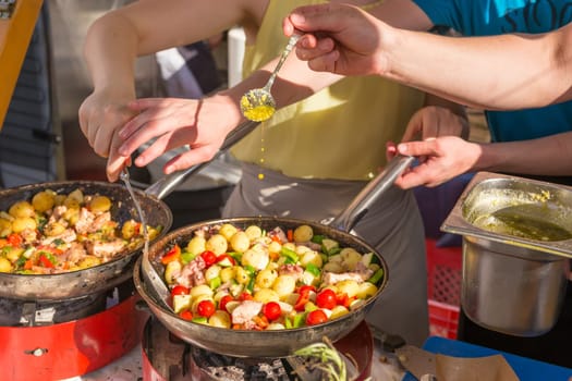 Cheff cooking traditional Mediterranean octopus with potatoes and vegetable on street stall on international street food festival of Odprta kuhna, Open kitchen event, in Ljubljana, Slovenia.