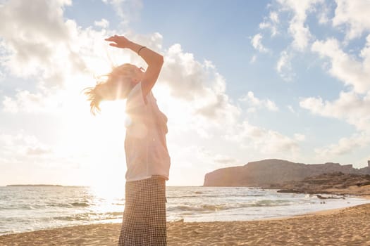 Relaxed woman enjoying sun, freedom and life an a beautiful sandy beach. Young lady feeling free, relaxed and happy. Vacations, freedom, happiness, enjoyment and well being.