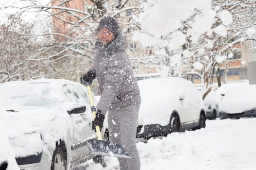 Man shoveling her parking lot after a winter snowstorm.