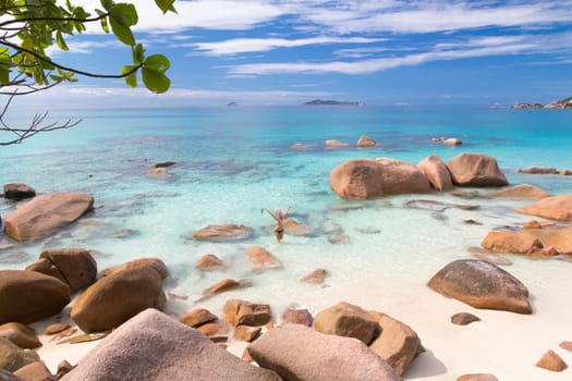 Happy woman arms rised wearing stylish bikini enjoying swimming and snorkeling at amazing Anse Lazio beach on Praslin Island, Seychelles. Summer vacations on picture perfect tropical beach concept.