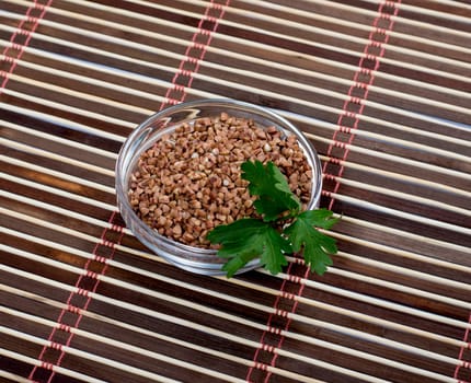 buckwheat in a saucer decorated with parsley, on a rug, a subject products