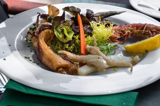 Close-up of various grilled fish varieties on a white plate in the restaurant..