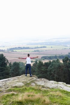 Young Man Standing On Rock With Outstretched Arms