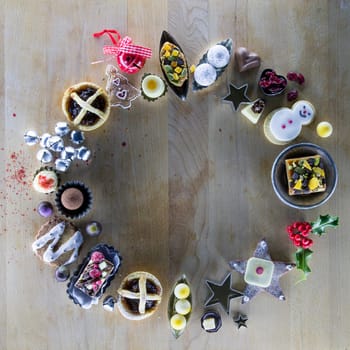 Christmas treats and accessories presented in a circle on a wooden chopping board.