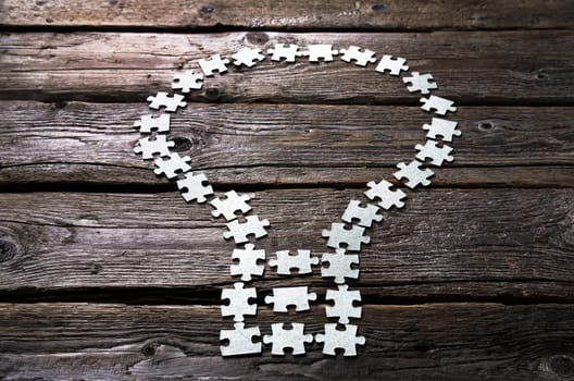 light bulb Lamp made of blank puzzle pieces on a textured wooden table.