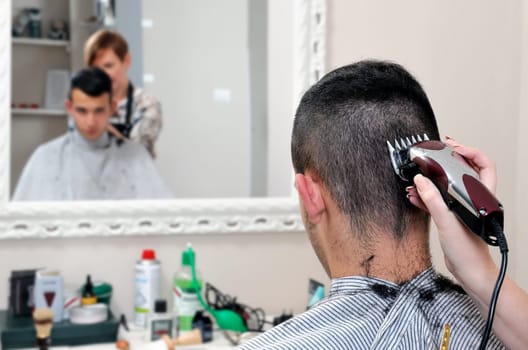 Barber shop that performs the haircut of a young boy with electric clippers.
