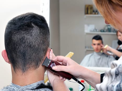 Barber shop that performs the haircut of a young boy with electric clippers.