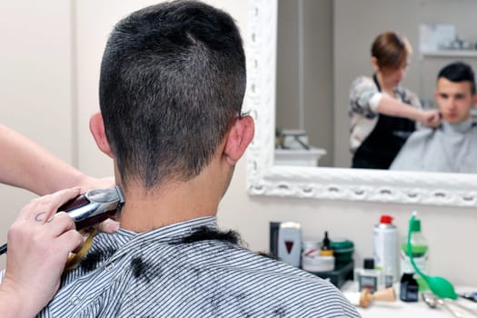 Barber shop that performs the haircut of a young boy with electric clippers.