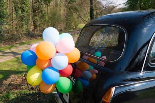 multi colored balloons on the back of a black vintage car