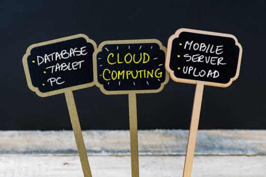 Concept message CLOUD COMPUTING written with chalk on wooden mini blackboard labels, defocused chalkboard and wood table in background