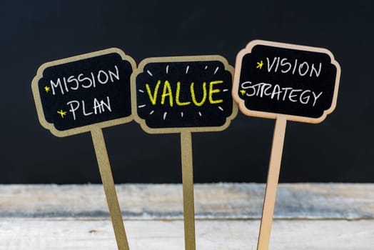 Concept message BRAND written with chalk on wooden mini blackboard labels, defocused chalkboard and wood table in background