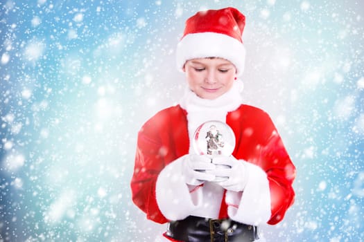 little boy holding christmas theme ornament on snowy background