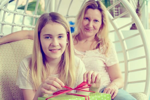 mother and daughterl with green gift box in a chair