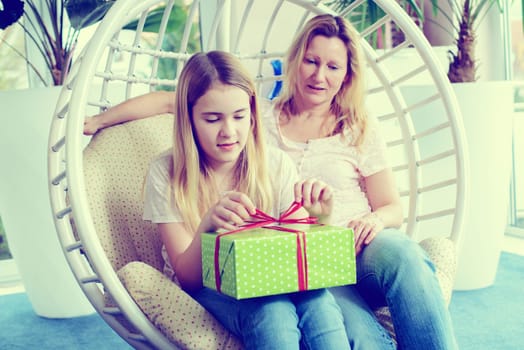 mother and daughterl with green gift box in a chair