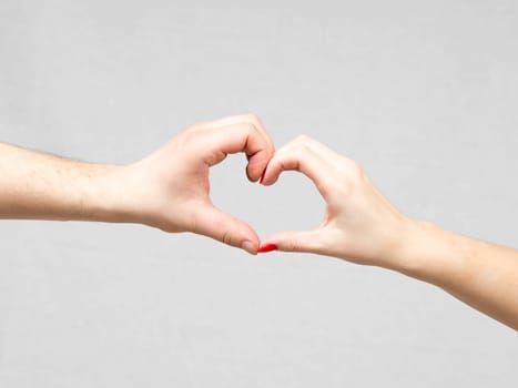 Female and Male Hands Making a Heart Shape on a gray background.