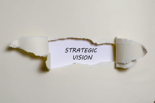 The word strategic vision appearing behind torn paper