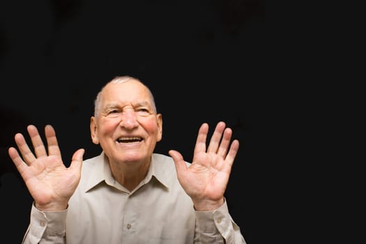 The happy elderly man on the black background