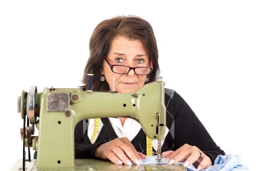 Beautiful senior woman with sewing machine isolated in white