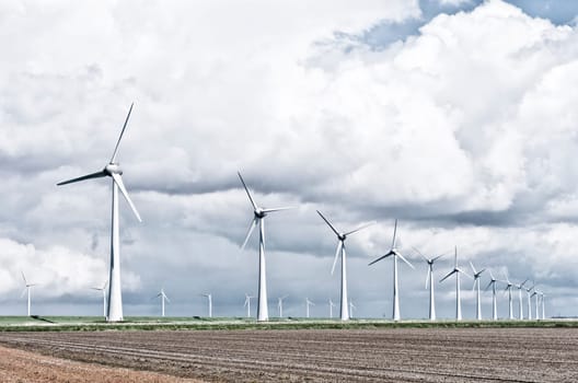 row wind turbines in an agricultural dutch landscape harsh filtered