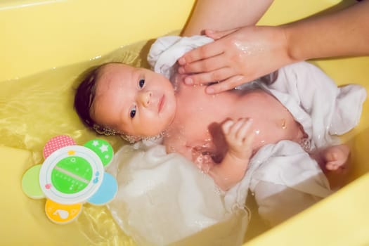 New born baby is receiving a bath from his mommy.