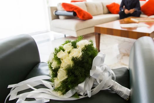 Close up view of a bridal bouquet with him sitting in the background groom