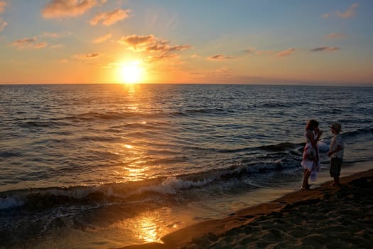 Girl in dress and boy playing at sunset on the beach