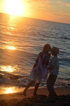Girl in dress and boy playing at sunset on the beach