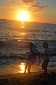 Girl in dress and boy playing at sunset on the beach