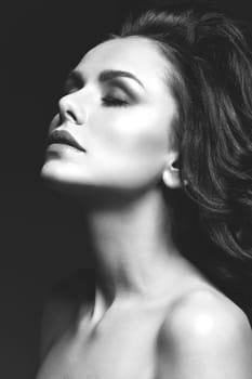 Closeup of beautiful young woman with long dark hair over black background. Copy space.