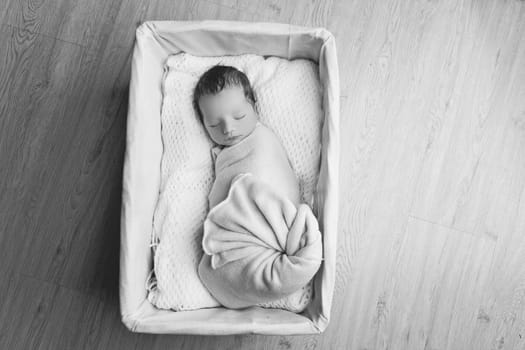 Adorable newborn baby boy sleeping in white basket. Copy space. Horizontal composition.