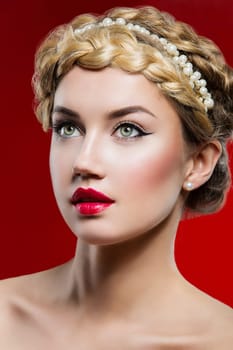 Beautiful young woman with full red lips and braid hairstyle. Beauty shot over red background.