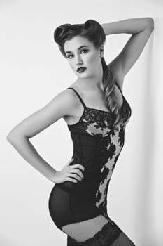 Beautiful retro pinup girl with red lips in black lace lingerie. Studio shot. Copy space. Monochrome.