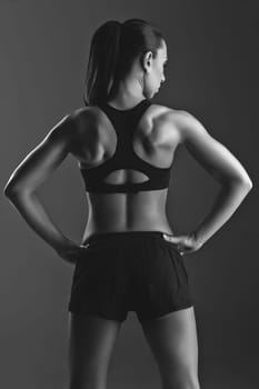 Sporty fit beautiful woman with muscle relief. Over black backgound. Copy space.