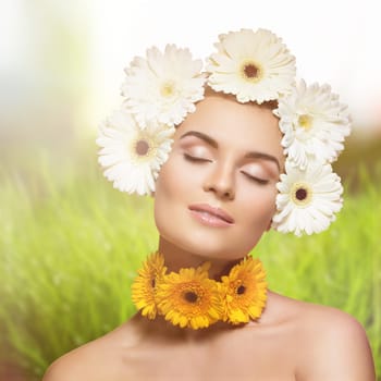 Beautiful young woman with gerberas on her heaad and neck. Beauty shot over natural sunny background