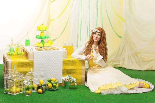 Beautiful young bride in yellow dress siiting near party table with flowers and wedding cake