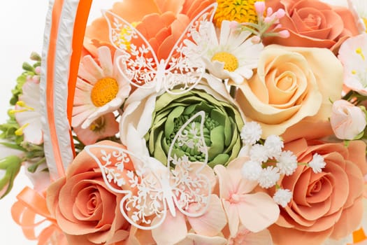 Wedding bouquet of artificial flowers in peachy, orange colours with lace butterflies on it